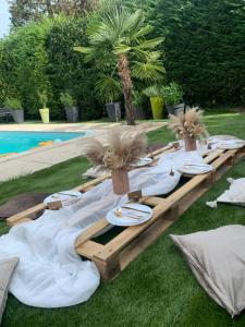 a picnic table with plates and palm trees next to a pool at Appartement proche marche de Noël de Strasbourg in Wolfisheim