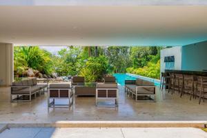 an outdoor patio with chairs and tables and a pool at Tropical Retreat Pools Golf Gym Jungle Views in Akumal