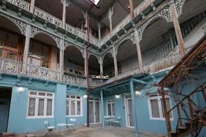 第比利斯Eva's Pavaroti的蓝色的建筑,设有椅子、阳台和桌子