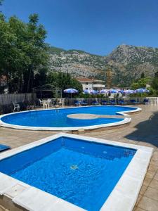 two swimming pools with tables and umbrellas in a resort at Apartman Mia in Risan