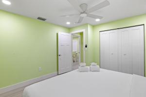 a bedroom with green walls and a bed with two chairs at Pirates Retreat Cottage at Palmview Inn of Sanibel in Sanibel