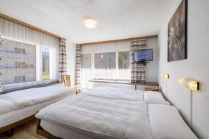 una camera con due letti, una TV e una finestra di Hostel Casa Franco a Sankt Moritz