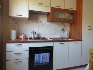 una cocina con armarios blancos y horno negro en Appartamento Maria Giovanna, en Giardini Naxos