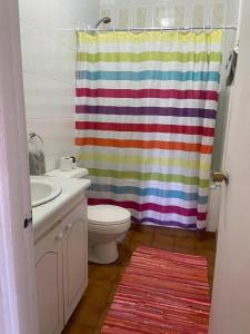 y baño con cortina de ducha colorida y aseo. en Departamento Recreo, en Viña del Mar