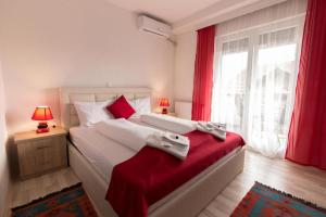 een slaapkamer met een groot bed met rode gordijnen en een raam bij Fantastik Ayaz Apartments in Ohrid