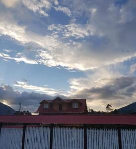 dom za płotem z pochmurnym niebem w obiekcie Hospedaje Lojada w mieście Oxapampa