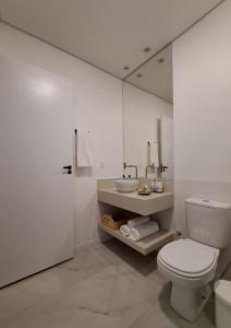 a white bathroom with a toilet and a sink at Casa dos Lírios in Alto Paraíso de Goiás