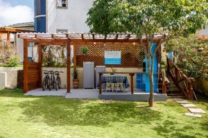 a pergola with a table and chairs in a yard at BANGALÔ NATUREZA in Florianópolis