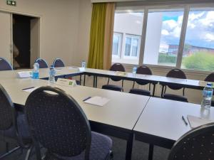 - une salle de conférence avec des tables, des chaises et des bouteilles d'eau dans l'établissement ibis Styles Rouen Nord-Barentin, à Barentin