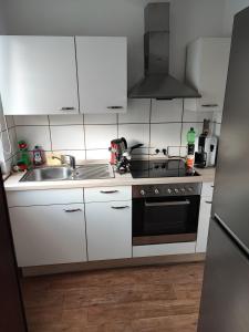 cocina con armarios blancos, fregadero y fogones en Apartment in der Rattenfängerstadt Hameln, en Hameln
