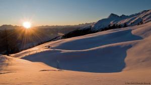 uma colina coberta de neve com o sol brilhando sobre ela em My Turrach Grünsee Chalet by S4Y em Turracher Höhe