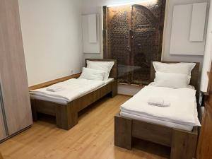 2 bedden in een kleine kamer met witte lakens bij Srce Sarajeva in Sarajevo
