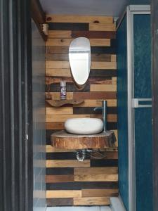a bathroom with a wooden wall with a sink and a mirror at HOSTAL MACONDO in Manizales