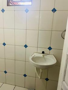 a white sink in a bathroom with white tiles at Casa Prox Praia de itapua in Salvador