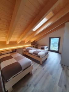 a bedroom with three beds in a room with wooden ceilings at La ciöda Malenca in Cave dʼArdesia
