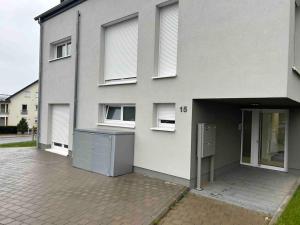 a white house with a door open and a building at Le rez de chaussée de chez Jade 