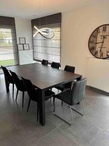 a dining room table with chairs and a large clock at Le rez de chaussée de chez Jade 