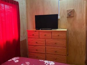 a bedroom with a dresser with a television on it at Cabañas Don Esteban in Tortel