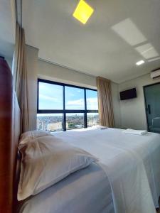 a bedroom with a large bed with a large window at Estudio Alto e Aconchegante no 32º andar do Vertigo in Campo Grande