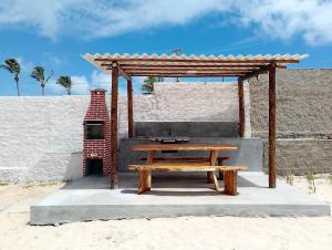 a wooden picnic table and a picnic shelter on the beach at Apartamento Casal beira mar, Ventos de Sibaúma in Tibau do Sul