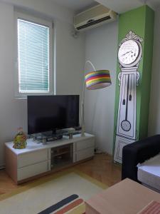 uma sala de estar com televisão e um relógio na parede em Artistica Apartment Skopje, 2 bdr em Skopje