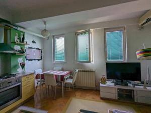 uma cozinha e sala de jantar com uma mesa e uma televisão em Artistica Apartment Skopje, 2 bdr em Skopje