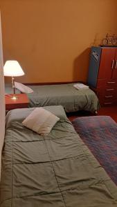 ein Schlafzimmer mit 2 Betten, einer Lampe und einer Kommode in der Unterkunft La Manquel - Casa y Yungas in Yerba Buena