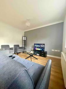 een woonkamer met een bank en een flatscreen-tv bij Chineham Retreat - Spacious Home For Leisure & Business Stays - Sleeps 8 in Sherborne Saint John