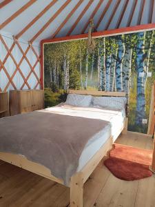a bed in a yurt with a mural of trees at Jurta Na Skraju Lasu 