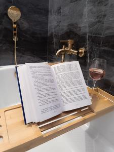an open book on a wooden tray with a glass of wine at Jurta Na Skraju Lasu 
