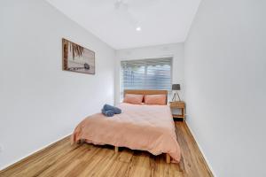 a white bedroom with a bed and a window at Cheltenham Delight - Renovated Two Bedroom Unit in Cheltenham