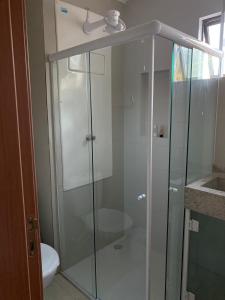 a glass shower in a bathroom with a toilet at Flat Porto do Galo in Porto De Galinhas