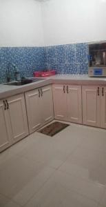 uma cozinha com armários brancos e azulejos azuis na parede em 4jMarte Home Stay em Imus