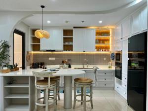 a kitchen with white cabinets and a island with bar stools at UPhoenix Home- HaDo Centrosa Garden in Ho Chi Minh City