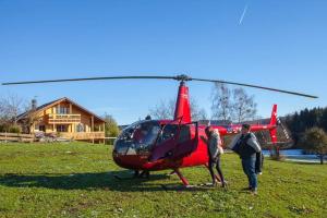 dwoje ludzi stojących obok czerwonego helikoptera w obiekcie Ferienhaus Alpenpanorama Chalet w mieście Mollenberg