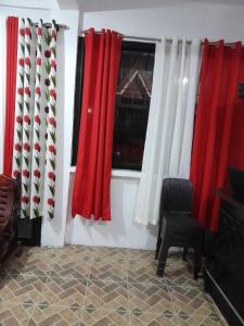 una camera con tende rosse e bianche e una sedia di 4jMarte Home Stay a Imus