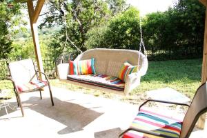 a porch swing with three pillows and two chairs at Guest House @ Silver Spur Dancehall Ruins~Bandera, TX. in Bandera