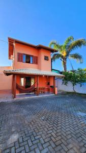 賓海洛的住宿－Partiu Praia SC- Pinheira，一座种植了棕榈树的橙色房子和车道