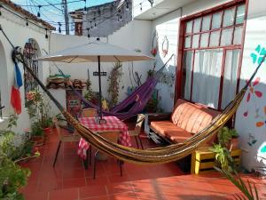 a hammock on a patio with a couch and an umbrella at Family Host HOSTEL in Villa de Leyva