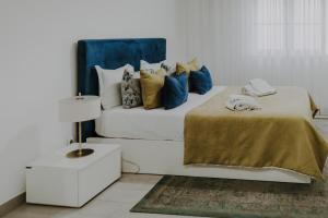 um quarto com uma cama branca com almofadas azuis e amarelas em Apartamentos Sol & Ria em Olhão