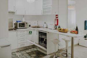 a white kitchen with a counter and a microwave at Apartamentos Sol & Ria in Olhão