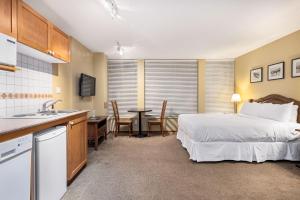 a bedroom with a bed and a kitchen with a table at Cascade Lodge suite with pool 2 hot tubs sauna gym in Whistler