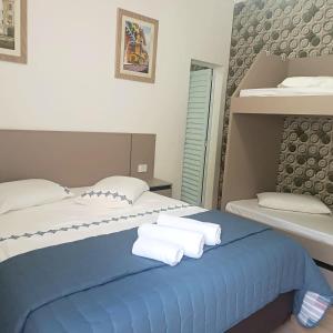 a bedroom with two beds and towels on a blue bed at Pousada Aconchego na Praia in Praia Grande