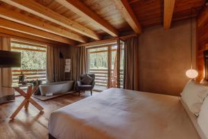 a bedroom with a bed and a tub and a chair at Au Charmant Petit Lac - Ecohotel Parc & Spa in Champoluc