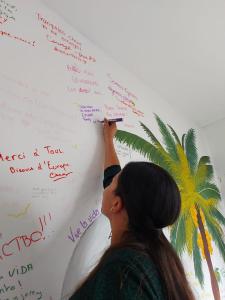 a woman writing on a whiteboard with a phone at Family Host HOSTEL in Villa de Leyva