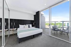 um quarto com uma cama grande e uma varanda em Premium Apartments Chatswood em Sidney