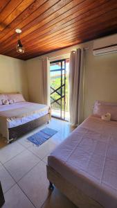 a bedroom with two beds and a sliding glass door at Partiu Praia SC in Guarda do Embaú