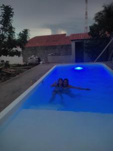 Dos niños en una piscina con luces azules en Pousada Vista Verde, en Paracuru