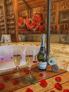Una botella de vino y dos copas en una mesa junto a una bañera. en Hotel Boutique El Duende Mantagua, en Quintero