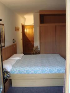 Schlafzimmer mit einem Bett mit blauer Decke in der Unterkunft Hotel Derby in Bormio